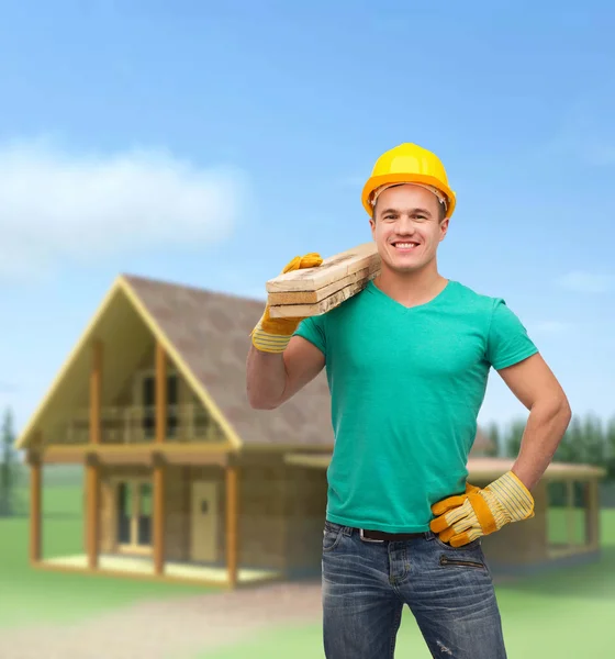 Ouvrier souriant dans un casque avec des planches en bois — Photo