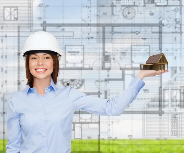 Businesswoman in helmet holding house on palm — Stock Photo, Image