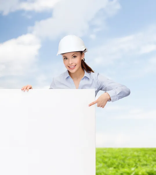 Businesswoman in helmet pointing finger to board — Stock Photo, Image