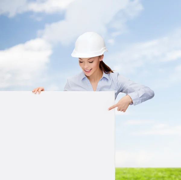 Businesswoman in helmet pointing finger to board — Stock Photo, Image