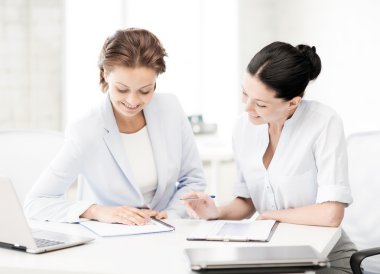 Two smiling businesswomen working in office clipart