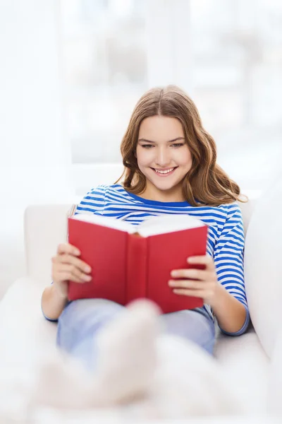 Uśmiechający się nastolatka czytanie książki na kanapie — Zdjęcie stockowe