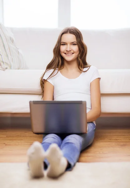 Улыбающаяся девочка-подросток с ноутбуком дома — стоковое фото