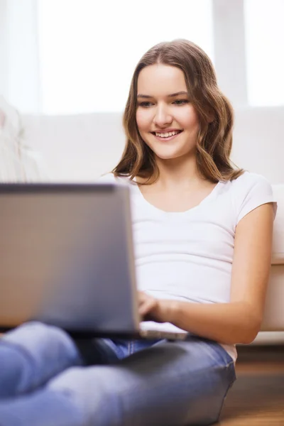 微笑着十几岁的女孩，有手提电脑在家里 — 图库照片