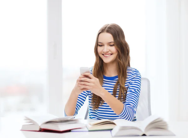 Chica estudiante sonriente con teléfono inteligente y libros — Foto de Stock