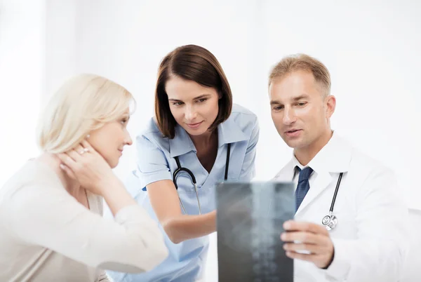 Médicos con paciente mirando rayos X — Foto de Stock