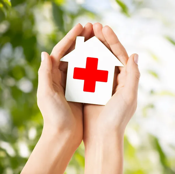 Handen met papier huis met Rode Kruis — Stockfoto