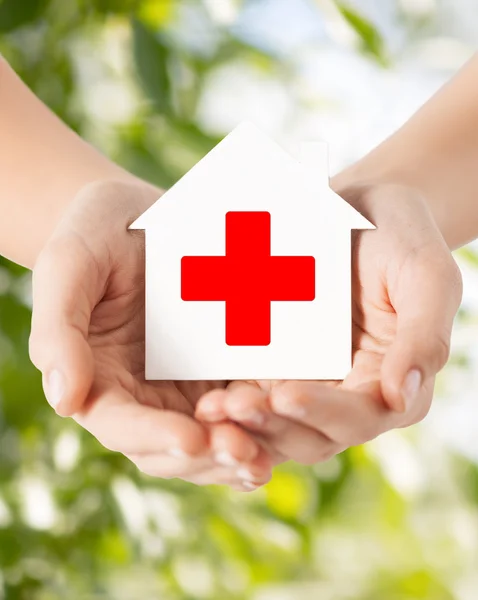 Hands holding paper house with red cross — Stock Photo, Image