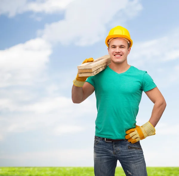 Trabalhador manual sorridente em capacete com tábuas de madeira — Fotografia de Stock