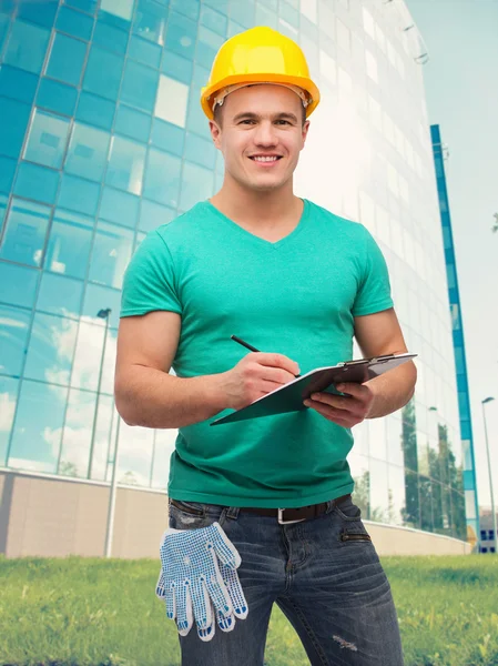 Lächelnder Mann mit Helm und Klemmbrett — Stockfoto