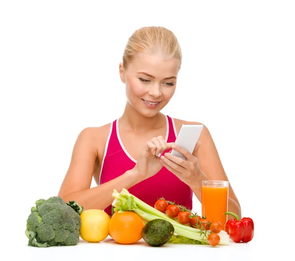 Жінка з овочами, вказуючи на смартфон — стокове фото