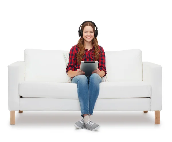 Flicka sitter på soffan med hörlurar och TabletPC — Stockfoto