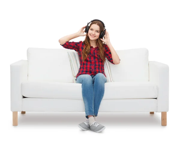 Teenager-Mädchen sitzt mit Kopfhörern auf Sofa — Stockfoto