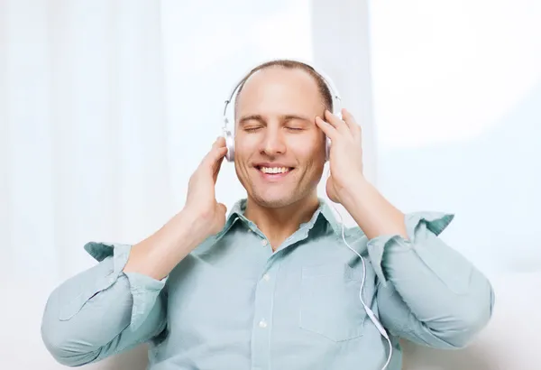 Glimlachende man met hoofdtelefoon luisteren naar muziek — Stockfoto