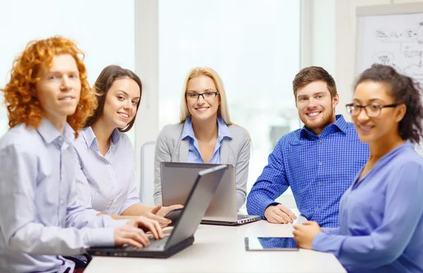 Glimlachend team met laptop en tafel pc-computers — Stockfoto