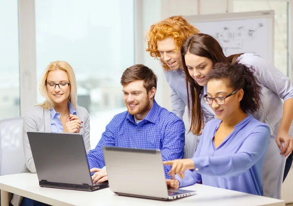 Equipo sonriente con computadoras portátiles en la oficina — Foto de Stock