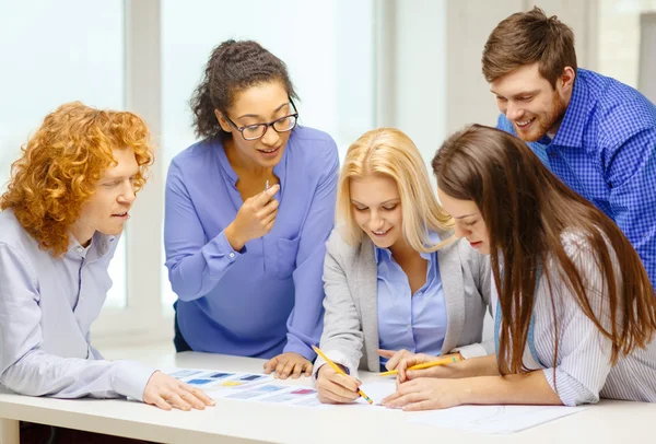 Smiling creative team looking over clothes designs — Stock Photo, Image