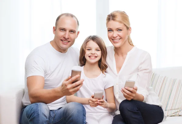 Pais e menina com smartphones em casa — Fotografia de Stock