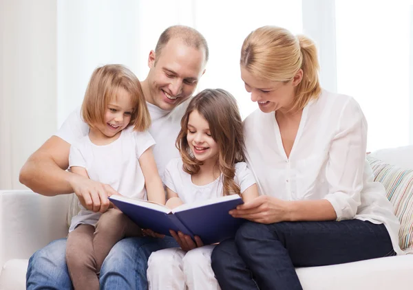 Smiling family and two little girls with book — Stock Photo, Image