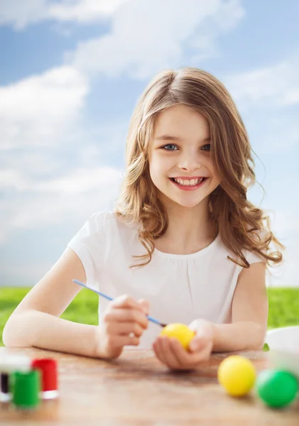 Улыбающаяся маленькая девочка раскрашивает яйца на Пасху — стоковое фото