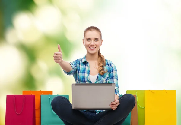 Chica sonriente con ordenador portátil comuter y bolsas de compras —  Fotos de Stock