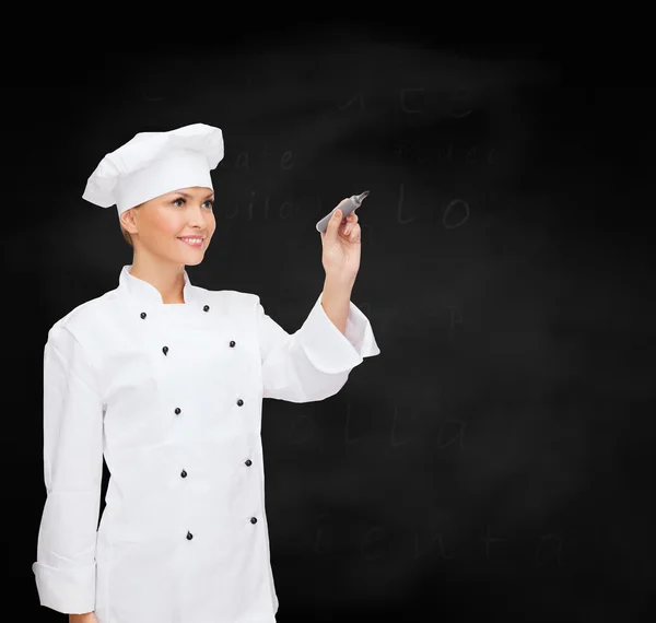 Sorrindo chef feminino escrevendo algo no ar — Fotografia de Stock