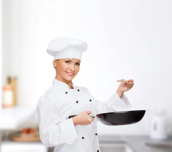 Chef feminino sorridente com panela e colher — Fotografia de Stock