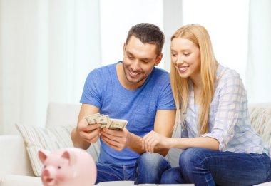 Smiling couple counting money at home clipart