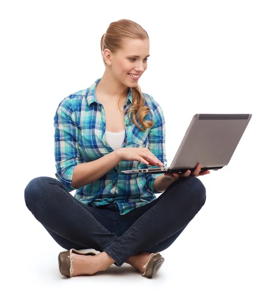 Улыбающаяся женщина с ноутбуком сидит на полу — стоковое фото