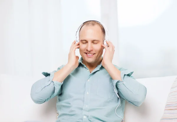 Glimlachende man met hoofdtelefoon luisteren naar muziek — Stockfoto