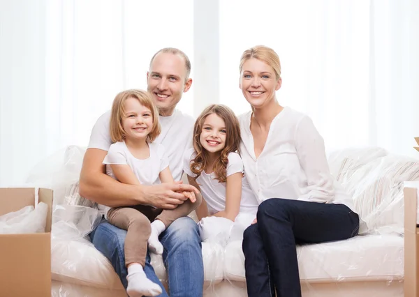 Lächelnde Eltern und zwei kleine Mädchen im neuen Zuhause — Stockfoto