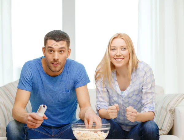 Smiling couple with popcorn cheering sports team — Stock Photo, Image