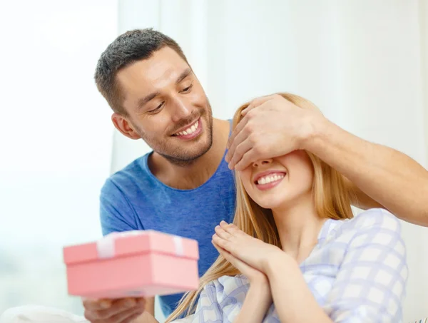 Sonriente hombre sorprende a su novia con presente — Foto de Stock