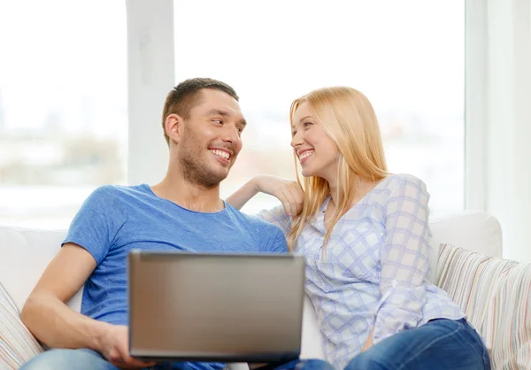 Улыбающаяся счастливая пара с ноутбуком дома — стоковое фото