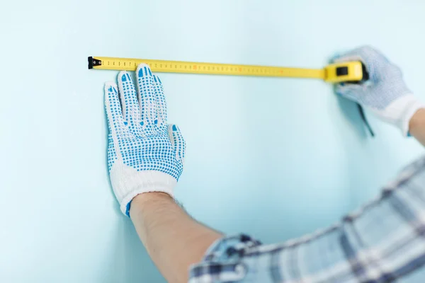 Gros plan du mâle dans des gants mesurant le mur avec du ruban adhésif — Photo