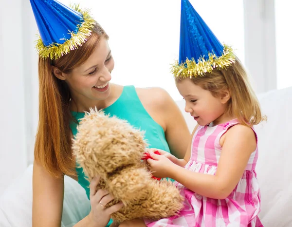 Mother and daughter in blue hats with teddy bear — Stock Photo, Image