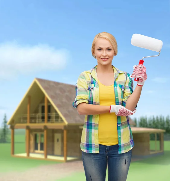 Lachende vrouw in handschoenen met verfroller — Stockfoto