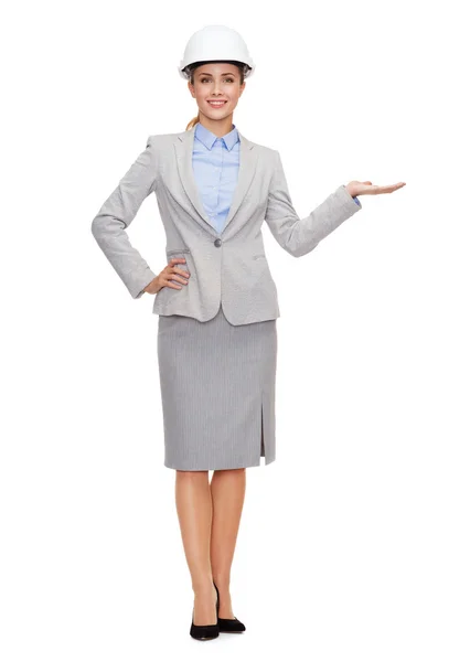 Businesswoman in helmet holding something on palm — Stock Photo, Image