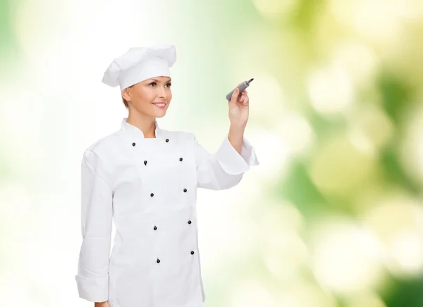 Sorrindo chef feminino escrevendo algo no ar — Fotografia de Stock