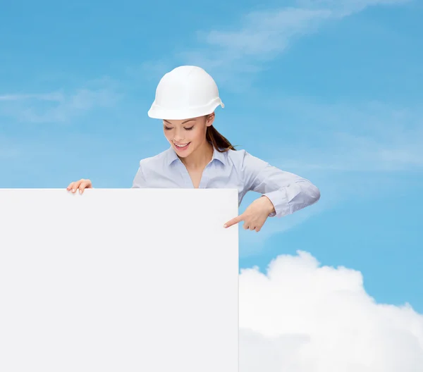 Businesswoman in helmet pointing finger to board — Stock Photo, Image