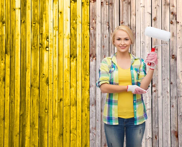 Femme souriante dans des gants avec rouleau de peinture — Photo