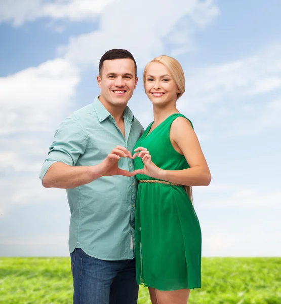 Smiling couple showing heart with hands — Stok fotoğraf