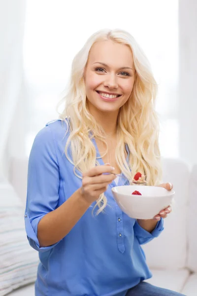 Mulher sorridente com tigela de muesli tomando café da manhã — Fotografia de Stock