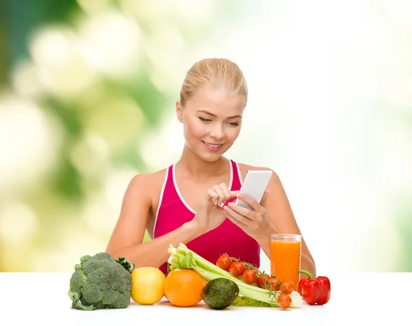 Женщина с овощами указывает на смартфон — стоковое фото