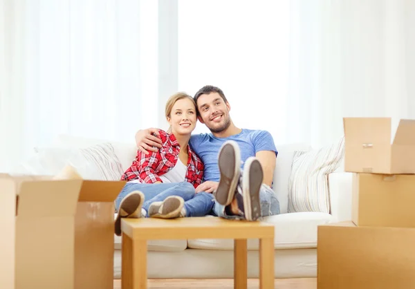 Pareja sonriente relajándose en un sofá en un nuevo hogar —  Fotos de Stock