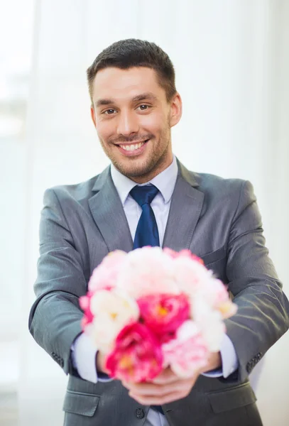 Smiling handsome man giving bouquet of flowers — Stock Photo, Image