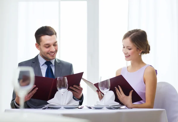 Smiling couple with menus at restaurant — Stock Photo, Image