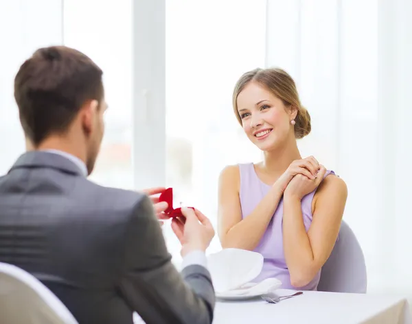 Excited young woman looking at boyfriend with ring — Stock Photo, Image