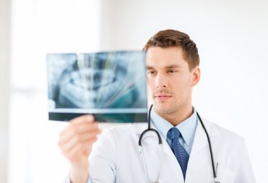 Concerned male doctor or dentist looking at x-ray clipart