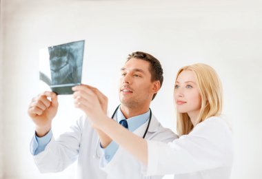 Smiling male doctor or dentist looking at x-ray clipart